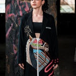 Woman wearing a black coat with colorful abstract design in an urban setting