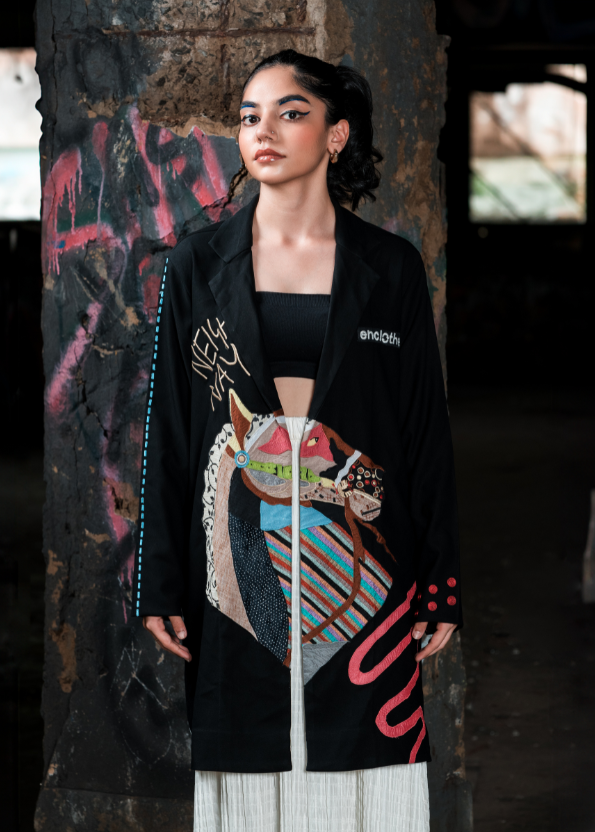 Woman wearing a black coat with colorful abstract design in an urban setting