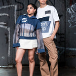 Two people standing in front of a graffiti-covered wall.
