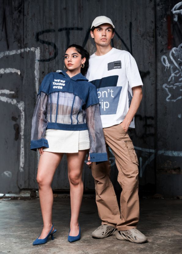 Two people standing in front of a graffiti-covered wall.