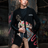 Man wearing a stylish jacket with colorful designs in a dark, textured setting