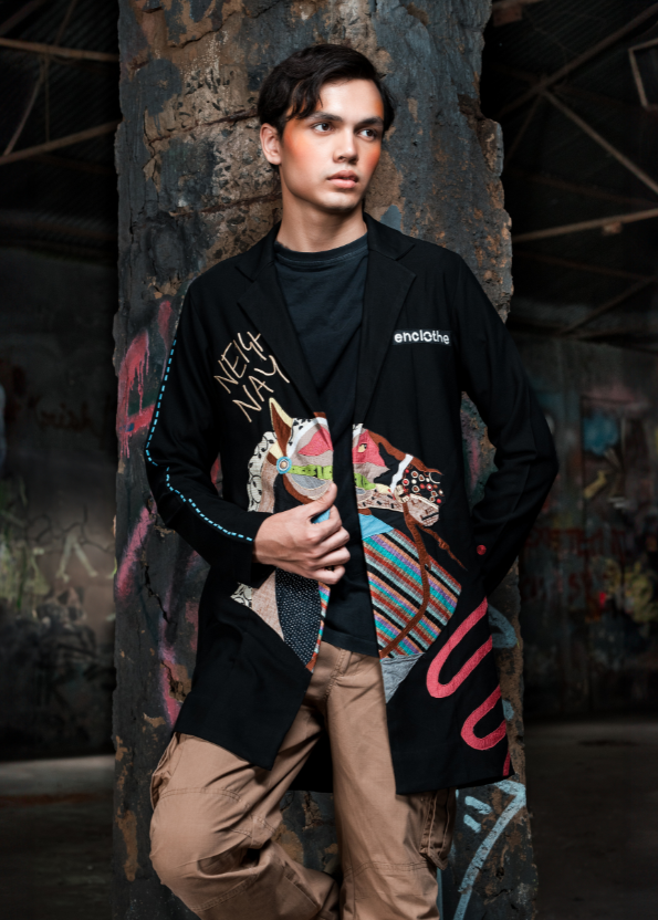 Man wearing a stylish jacket with colorful designs in a dark, textured setting