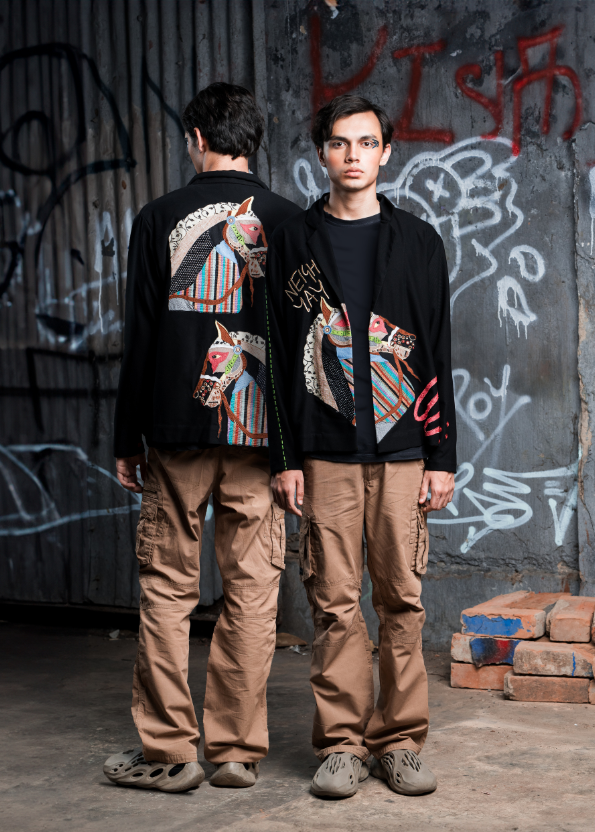 Two individuals wearing matching outfits with colorful designs in front of a graffiti-covered wall.