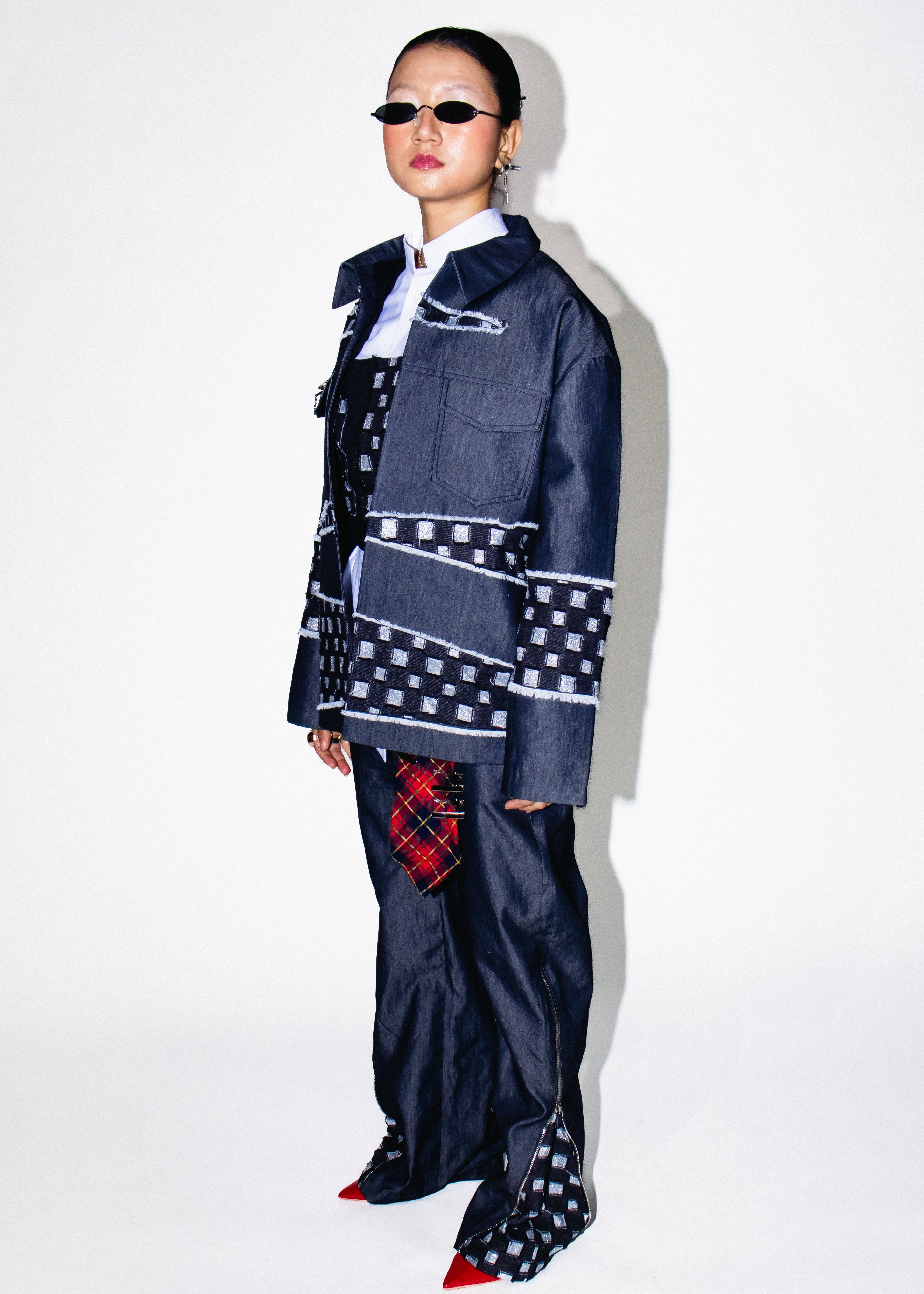 Person wearing a unique outfit with a denim jacket and plaid pants on a white background