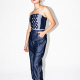 Woman wearing a strapless top and high-waisted pants with a white background