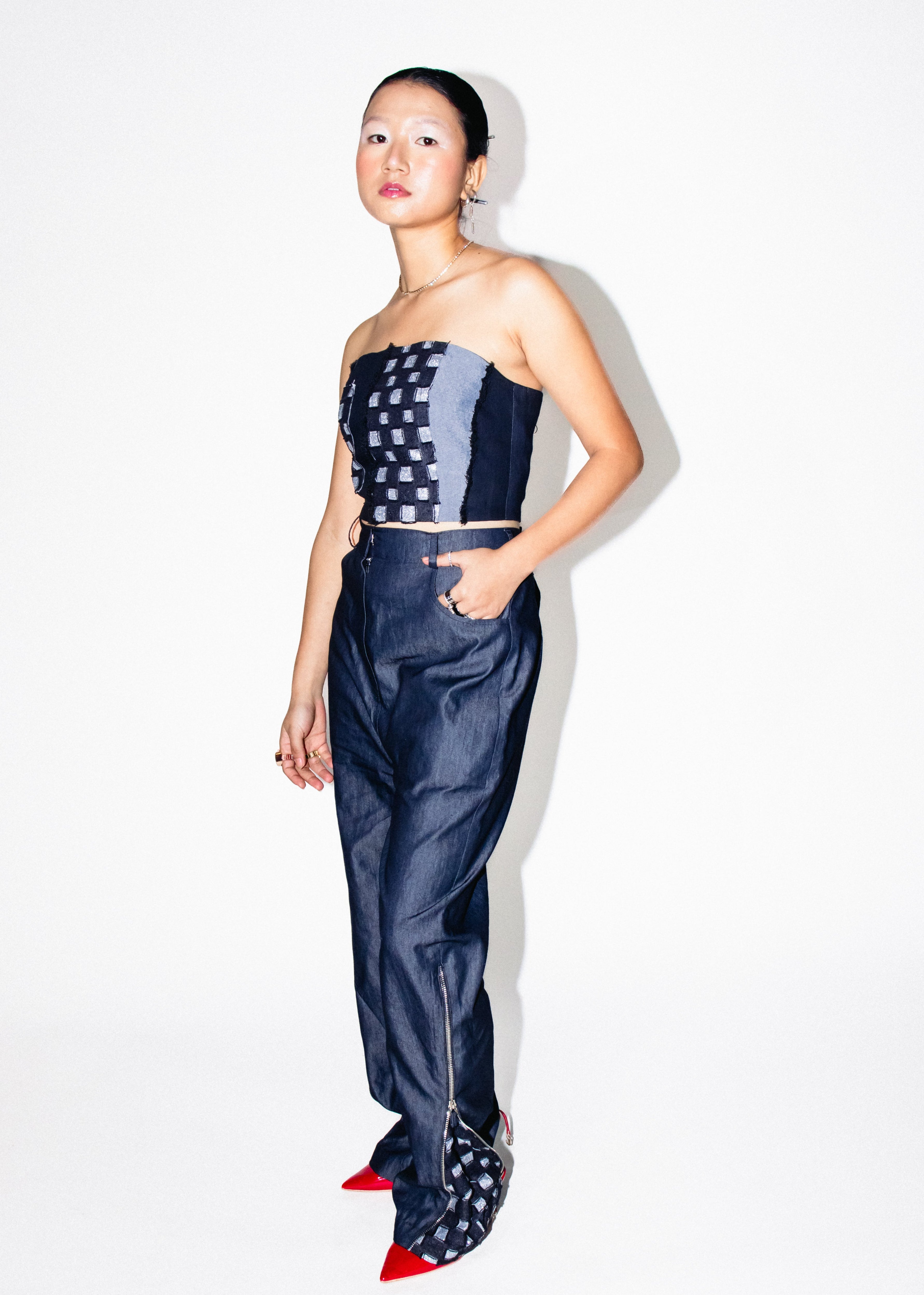 Woman wearing a strapless top and high-waisted pants with a white background