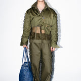 Person wearing a green military-style outfit with a blue bag on a white background