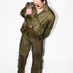 Person wearing a green military-style outfit with spiky details on a white background