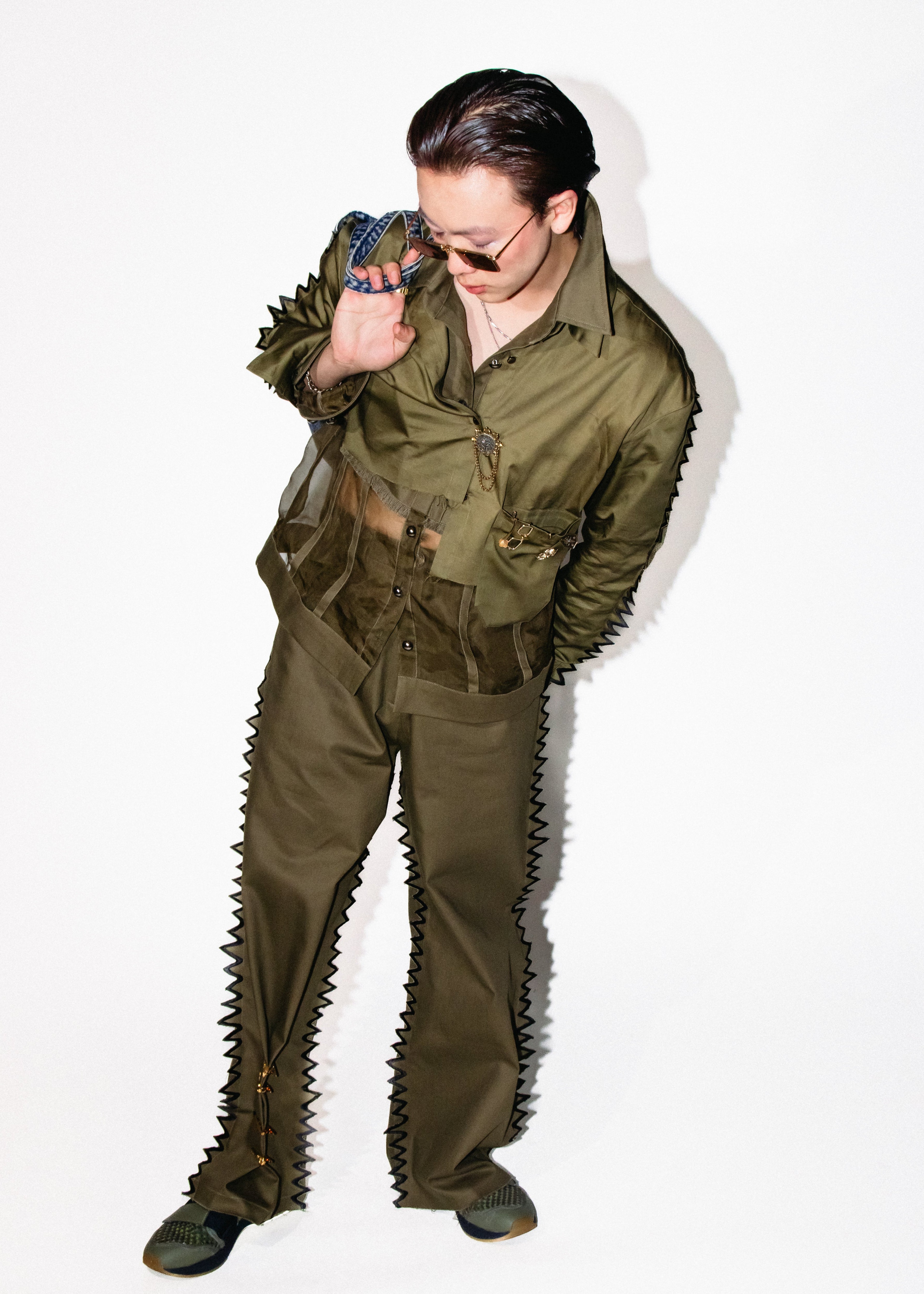 Person wearing a green military-style outfit with spiky details on a white background