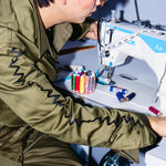 Person working on a sewing machine with colorful thread spools.
