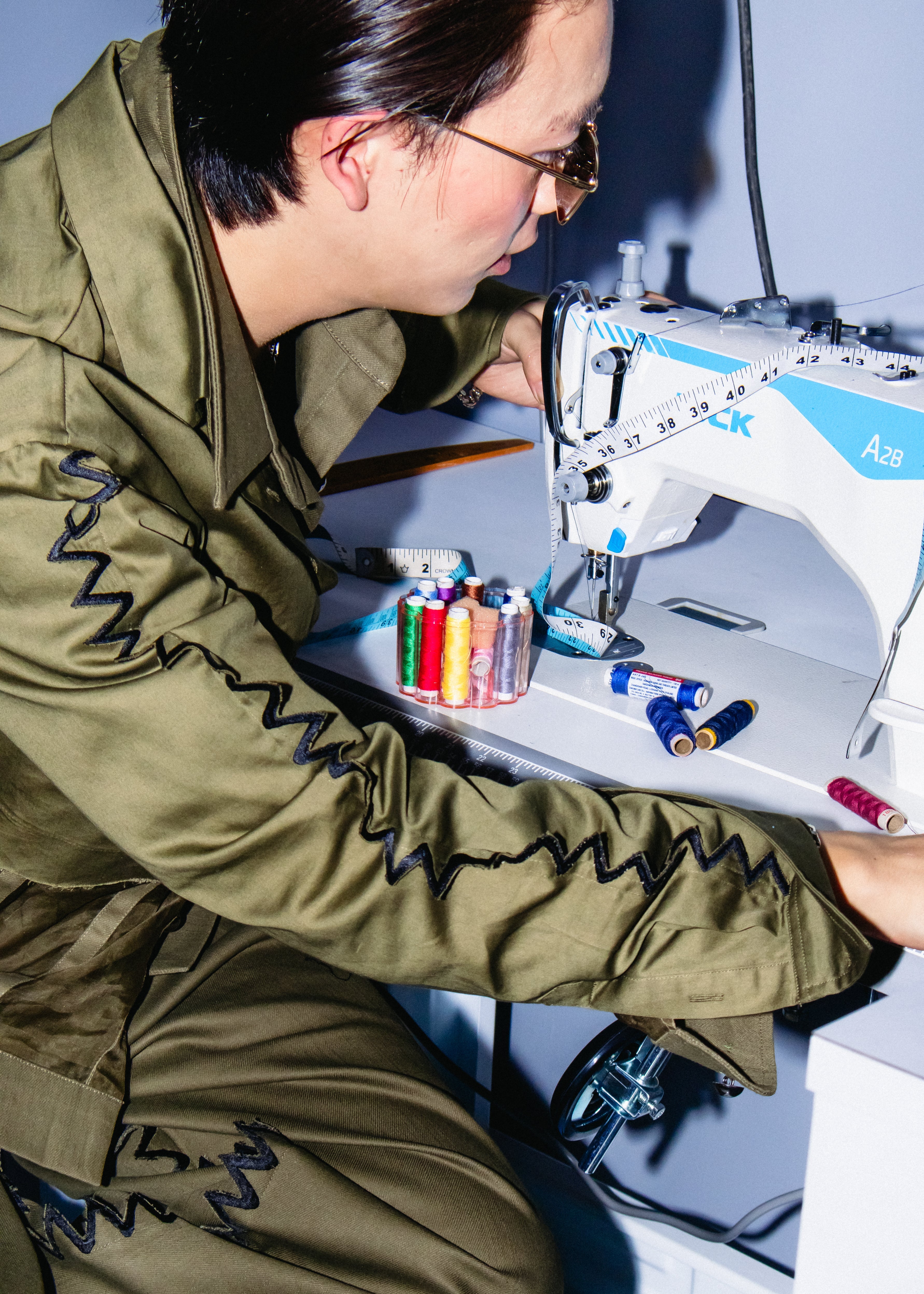 Person working on a sewing machine with colorful thread spools.