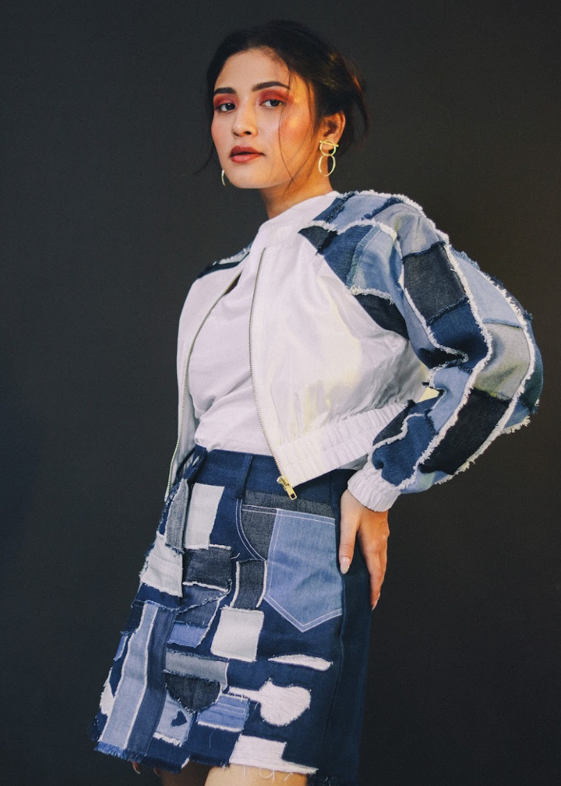 Person wearing a patchwork denim outfit against a black background
