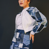 Person wearing a patchwork denim outfit against a black background