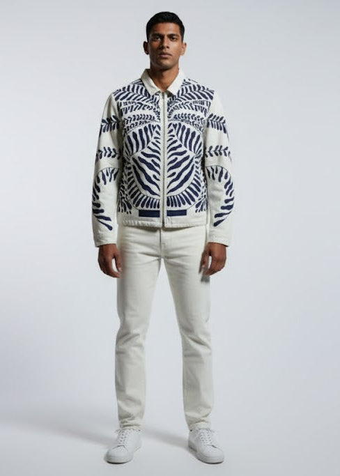 Person wearing a patterned jacket and white pants on a gray background