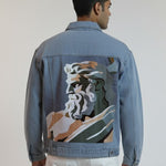 Man wearing a blue denim jacket with a colorful back design on a plain background
