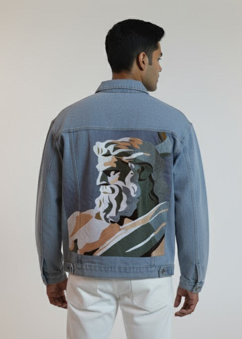 Man wearing a blue denim jacket with a colorful back design on a plain background