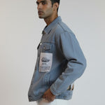 Man wearing a denim jacket with a patch on a plain background