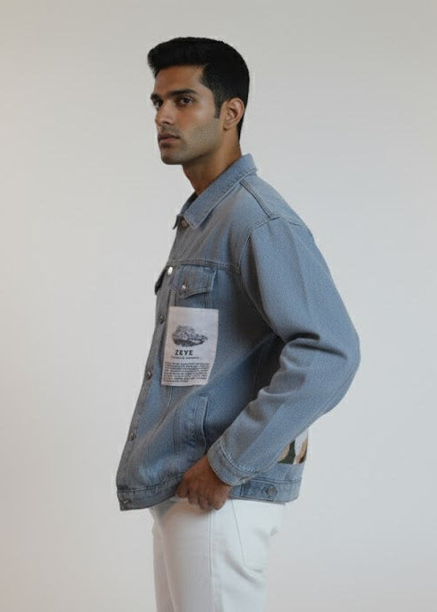 Man wearing a denim jacket with a patch on a plain background