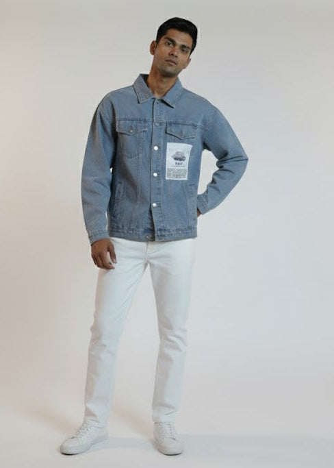 Man wearing a denim jacket and white pants on a plain background