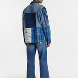 Person wearing a patchwork denim jacket and jeans on a white background