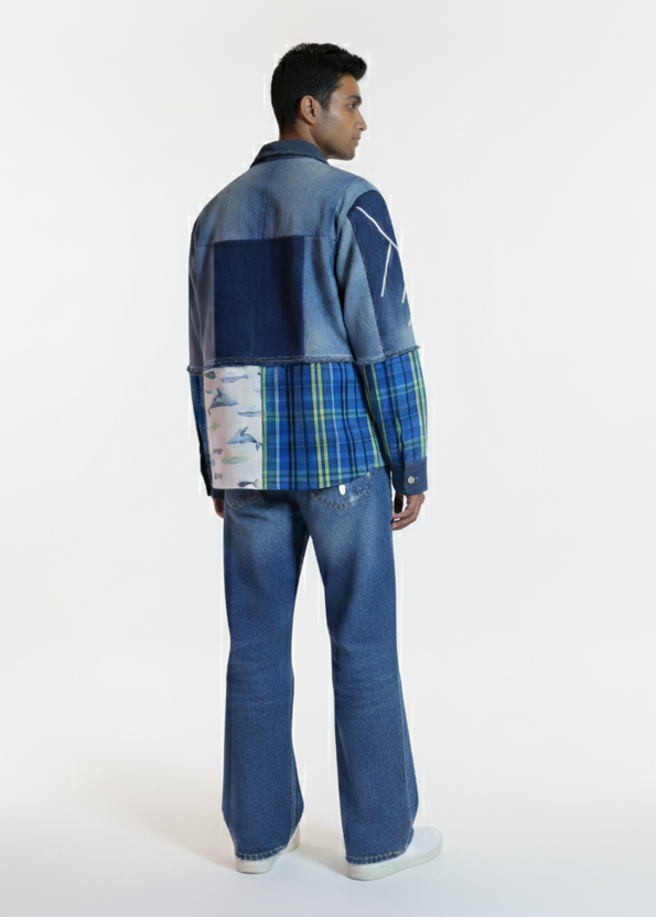 Person wearing a patchwork denim jacket and jeans on a white background