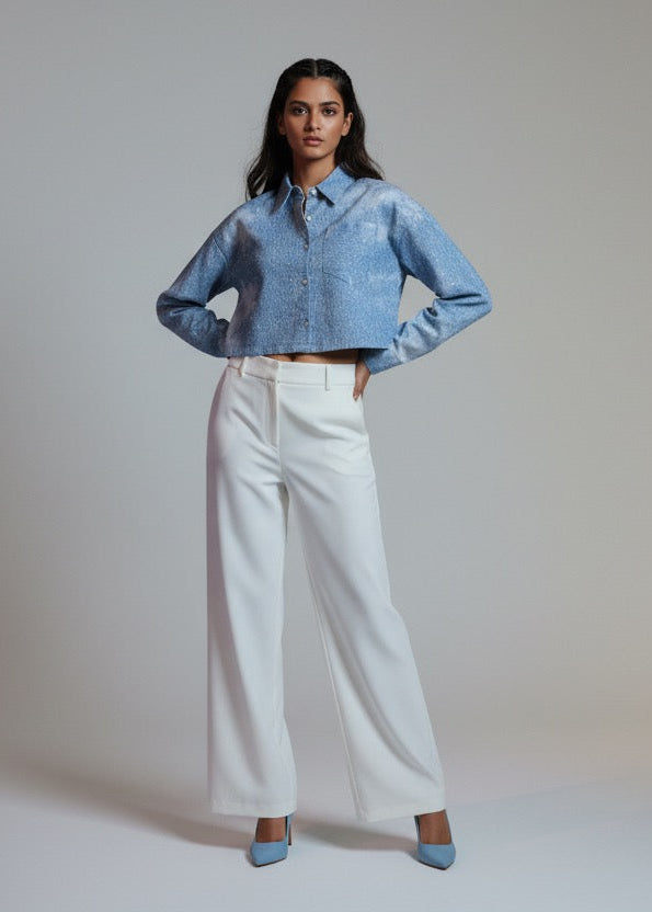 Woman wearing a denim jacket and white pants against a plain background