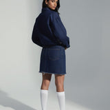 Person wearing a navy blue sweater and skirt with white knee-high socks on a plain background