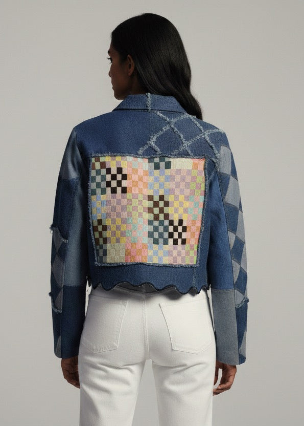 Person wearing a denim jacket with a colorful patch on the back against a gray background
