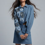 Woman wearing a blue denim outfit with floral patterns on a gray background
