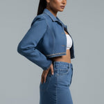 Woman wearing a denim jacket and skirt on a gray background
