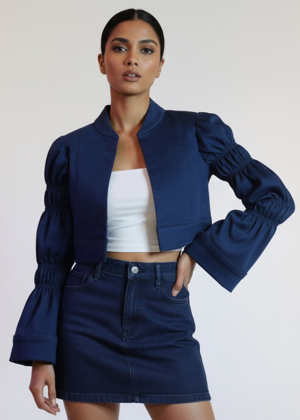 Woman wearing a navy blue jacket and skirt with a white top against a plain background