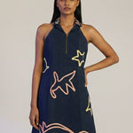 Woman wearing a navy dress with colorful designs on a plain background