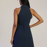 Woman wearing a navy dress and cap on a plain background