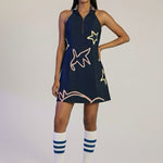 Woman wearing a navy dress with white star patterns on a plain background