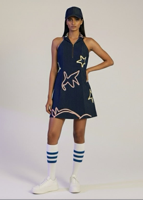 Woman wearing a navy dress with white star patterns on a plain background