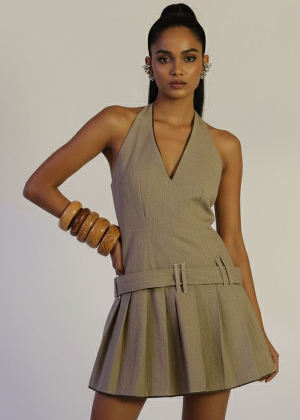 Woman wearing a beige halter dress against a plain background