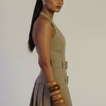 Woman wearing a beige dress with a belt on a plain background