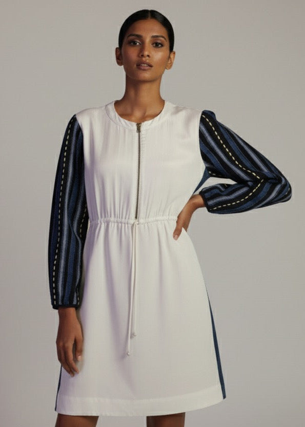 Woman wearing a white dress with blue accents on a plain background
