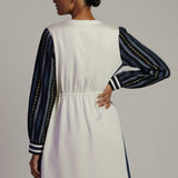 Woman wearing a white dress with navy accents on a plain background
