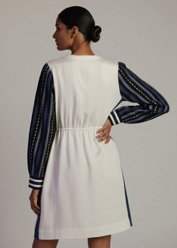 Woman wearing a white dress with navy accents on a plain background