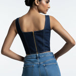 Woman wearing a blue denim jumpsuit on a white background