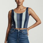 Woman wearing a striped sleeveless top and blue jeans on a plain background