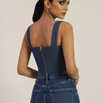 Woman wearing a blue denim jumpsuit on a beige background