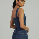 Woman wearing a blue denim dress against a gray background