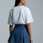 Person wearing a white top and blue skirt on a gray background