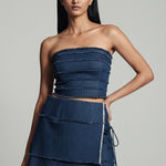 Woman wearing a denim strapless top and skirt on a gray background