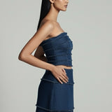 Woman wearing a blue strapless top and skirt against a gray background