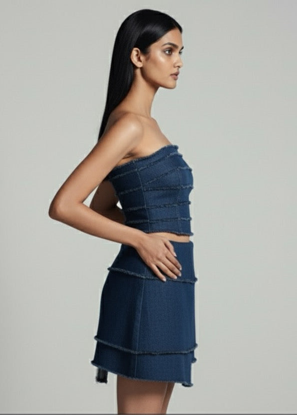 Woman wearing a blue strapless top and skirt against a gray background