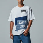 Man wearing a white t-shirt with a blue graphic and text on a gray background