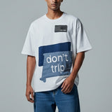 Man wearing a white t-shirt with a blue graphic and text on a gray background